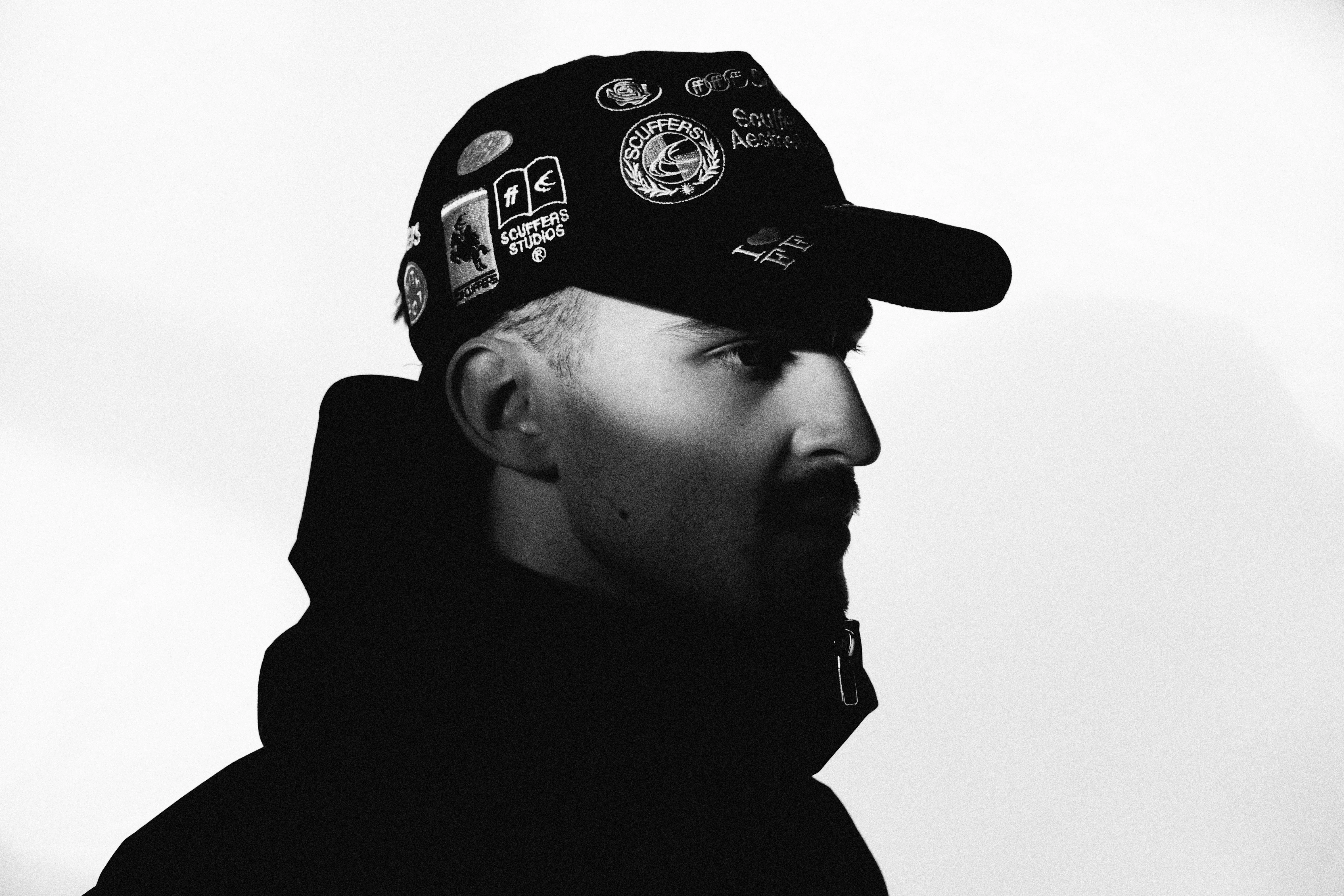 Black and white close-up side profile with sticker-covered cap against white backdrop