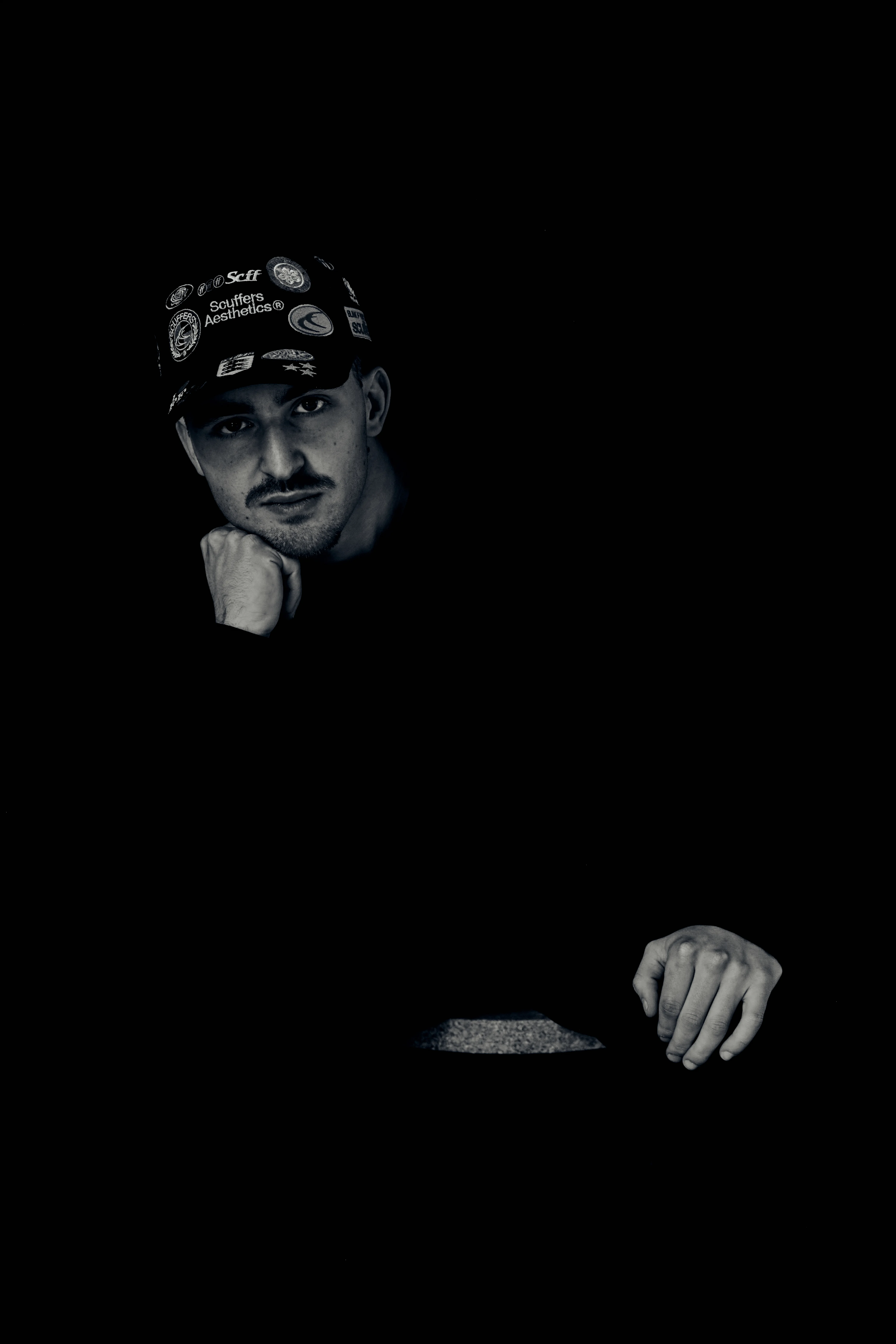 Dark noir portrait with face and hand emerging from black background
